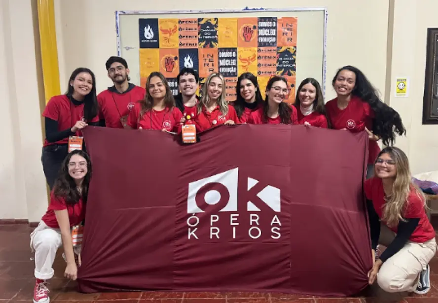 Equipe da Ópera Krios reunida com a bandeira da empresa